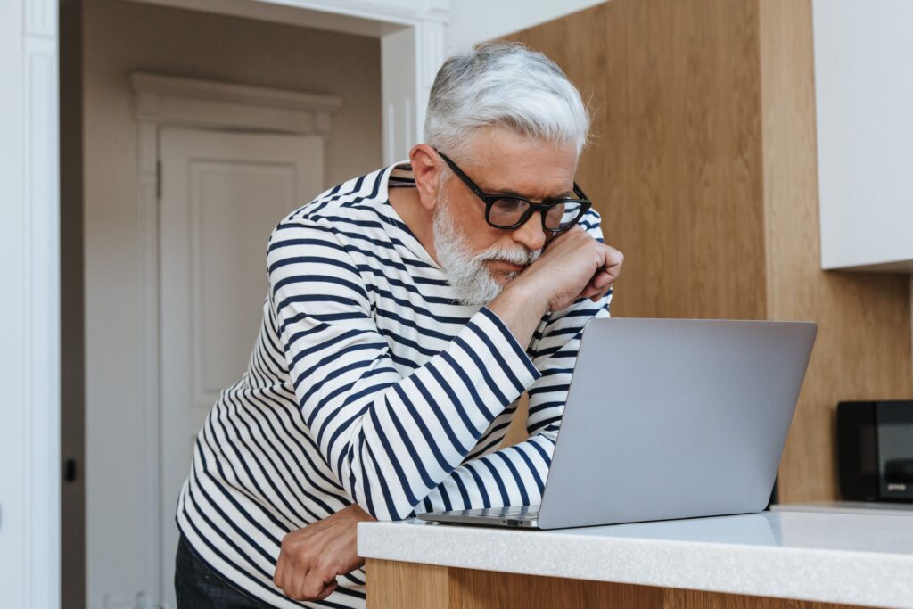 Older adult concentrating while working on a laptop