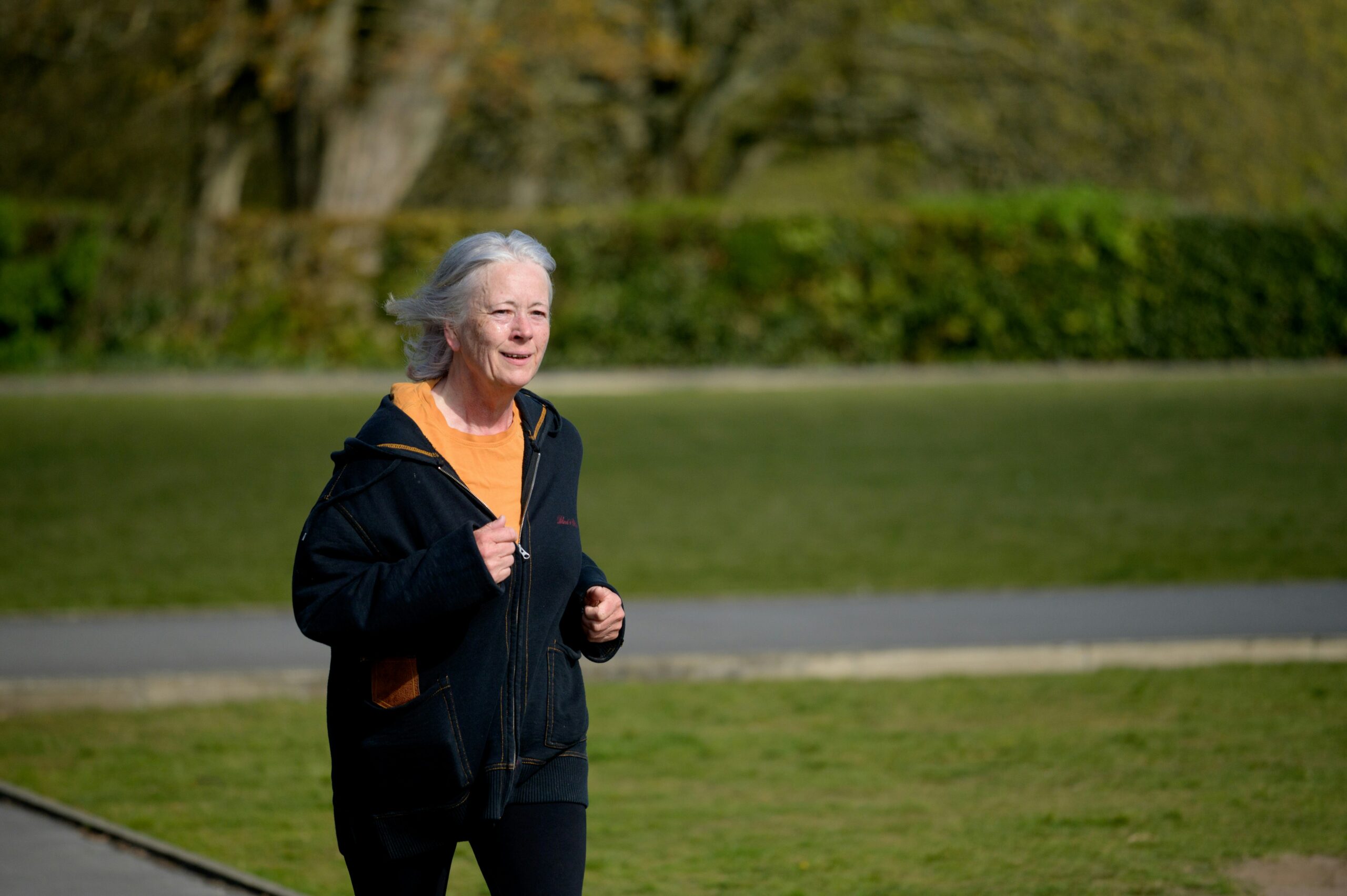 Middle-aged adult jogging along a green park path