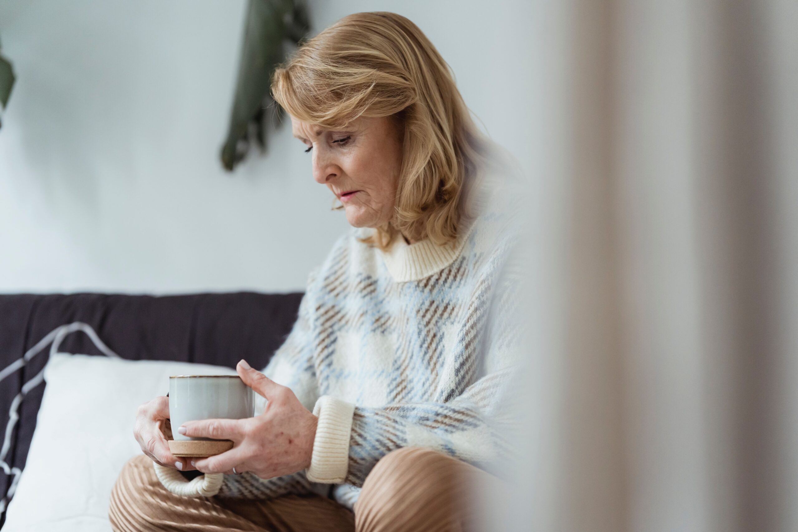 Older woman sitting thoughtfully on her bed after a restless night